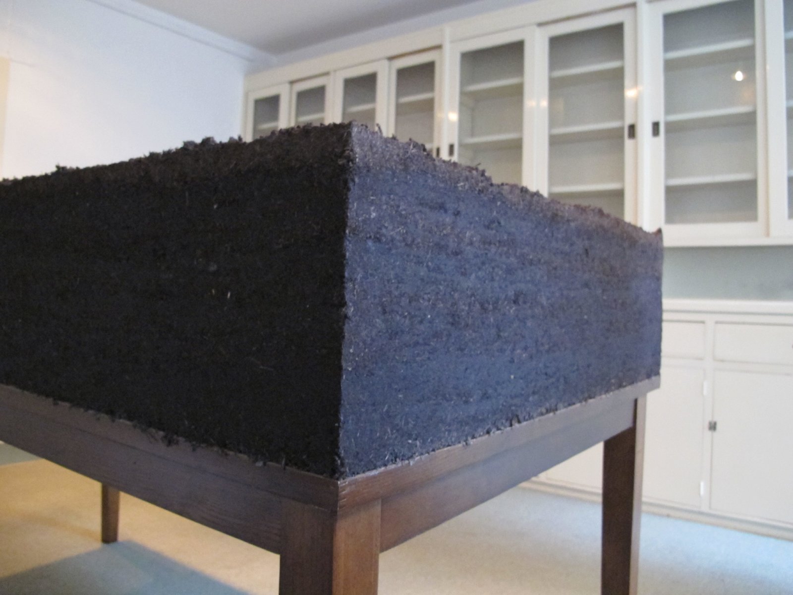 Abbas Akhavan, Dirt/Table (detail), 2012, topsoil, water, wooden table, 42 x 36 x 72 in. (106 x 91 x 182 cm). Installation view, Study for a Garden, Delfina Foundation, London, UK, 2012
