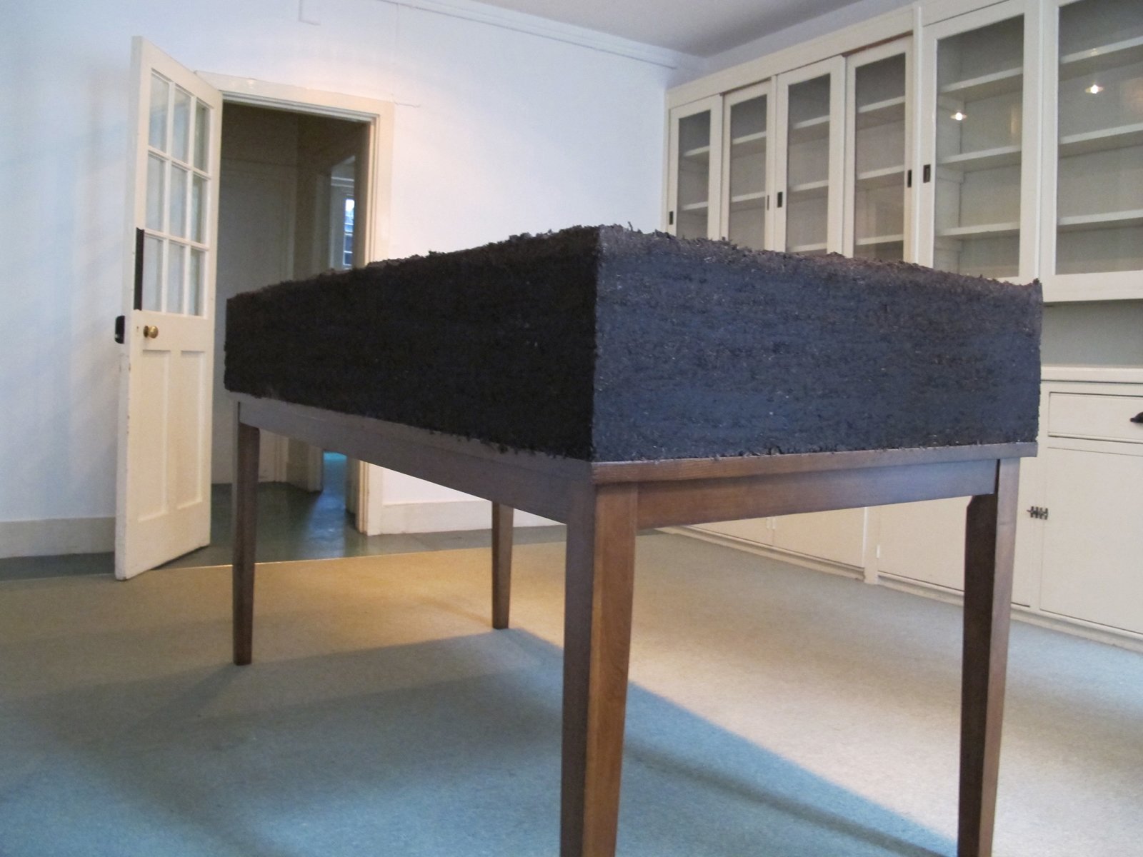 Abbas Akhavan, Dirt/Table, 2012, topsoil, water, wooden table, 42 x 36 x 72 in. (106 x 91 x 182 cm). Installation view, Study for a Garden, Delfina Foundation, London, UK, 2012