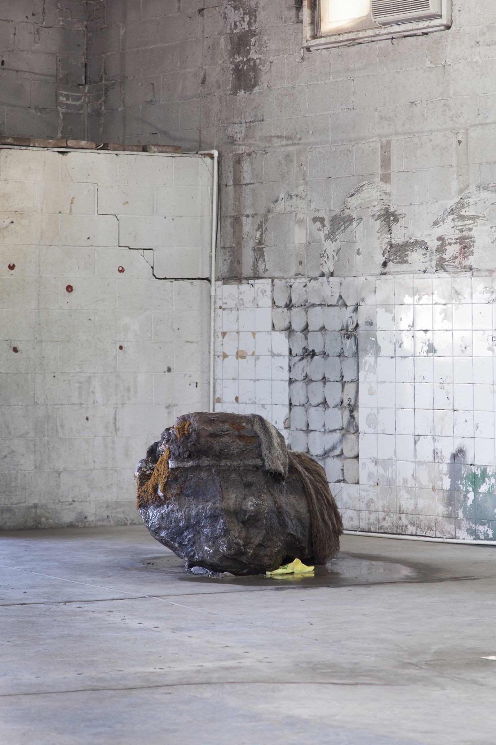 Abbas Akhavan, Untitled, 2018, erratic boulder, water system, vintage fur coat, plastic bag, 40 x 30 x 31 in. (102 x 75 x 80 cm). Installation view, Folly, Vie d’ange, Montreal, 2018