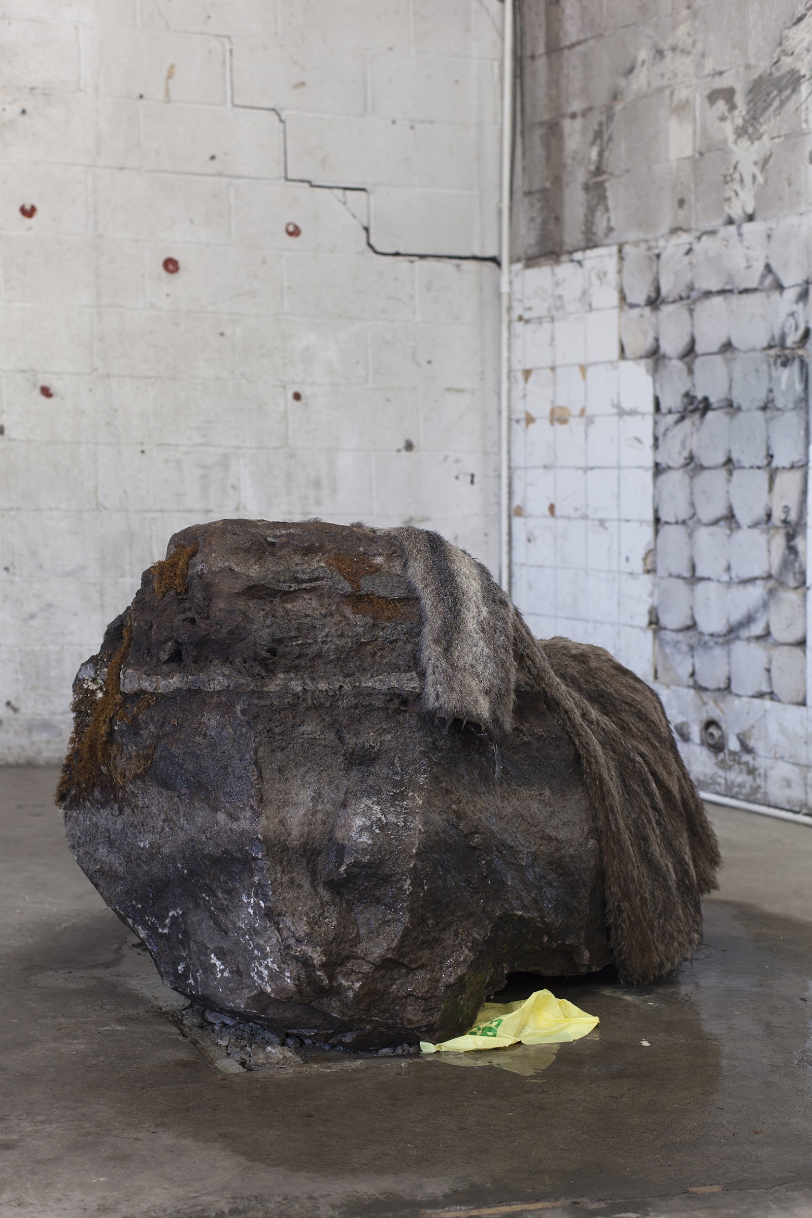 Abbas Akhavan, Untitled, 2018, erratic boulder, water system, vintage fur coat, plastic bag, 40 x 30 x 31 in. (102 x 75 x 80 cm). Installation view, Folly, Vie d’ange, Montreal, 2018