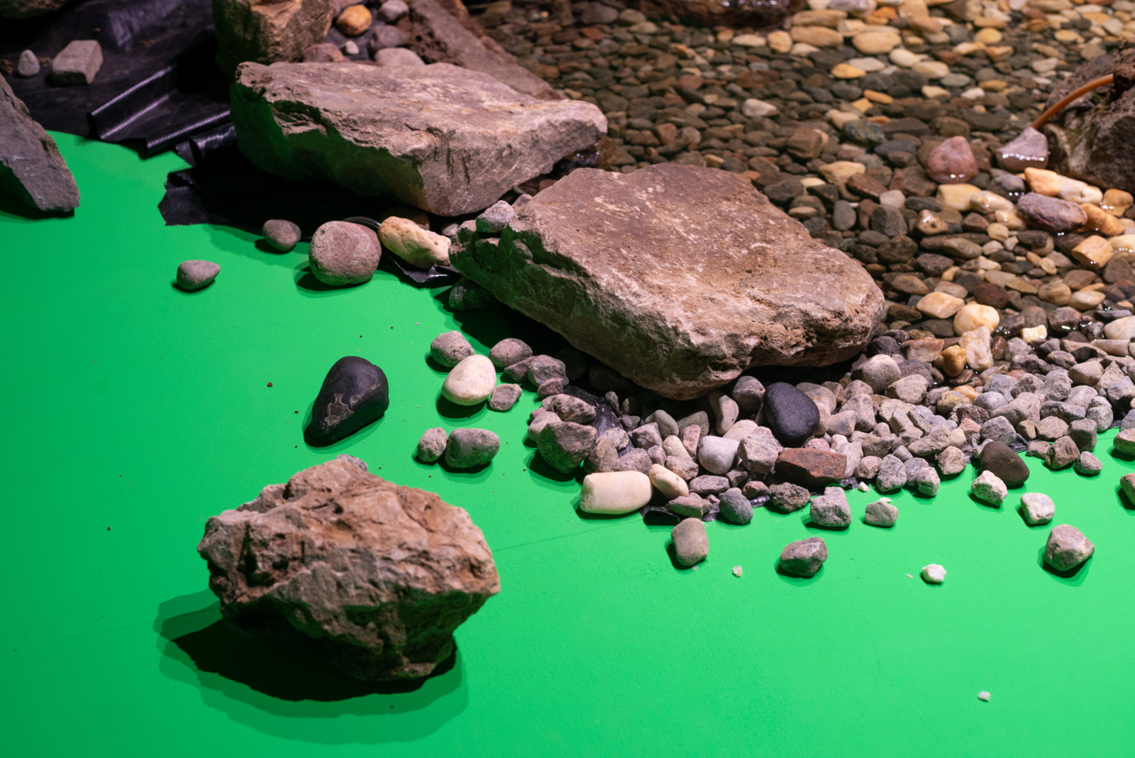 Abbas Akhavan, spill (detail), 2021, boulders, rocks, river stones, water, PVC pond membrane, water pumps and tubing, pressure treated lumber, baltic birch plywood, various hardware, chroma key paint, full spectrum L.E.D. lightbulbs, 144 x 144 x 144 in. (366 x 366 x 366 cm). Installation view, Sensing Nature, Momenta Biennale at Phi Foundation for Contemporary Art, Montreal, Canada