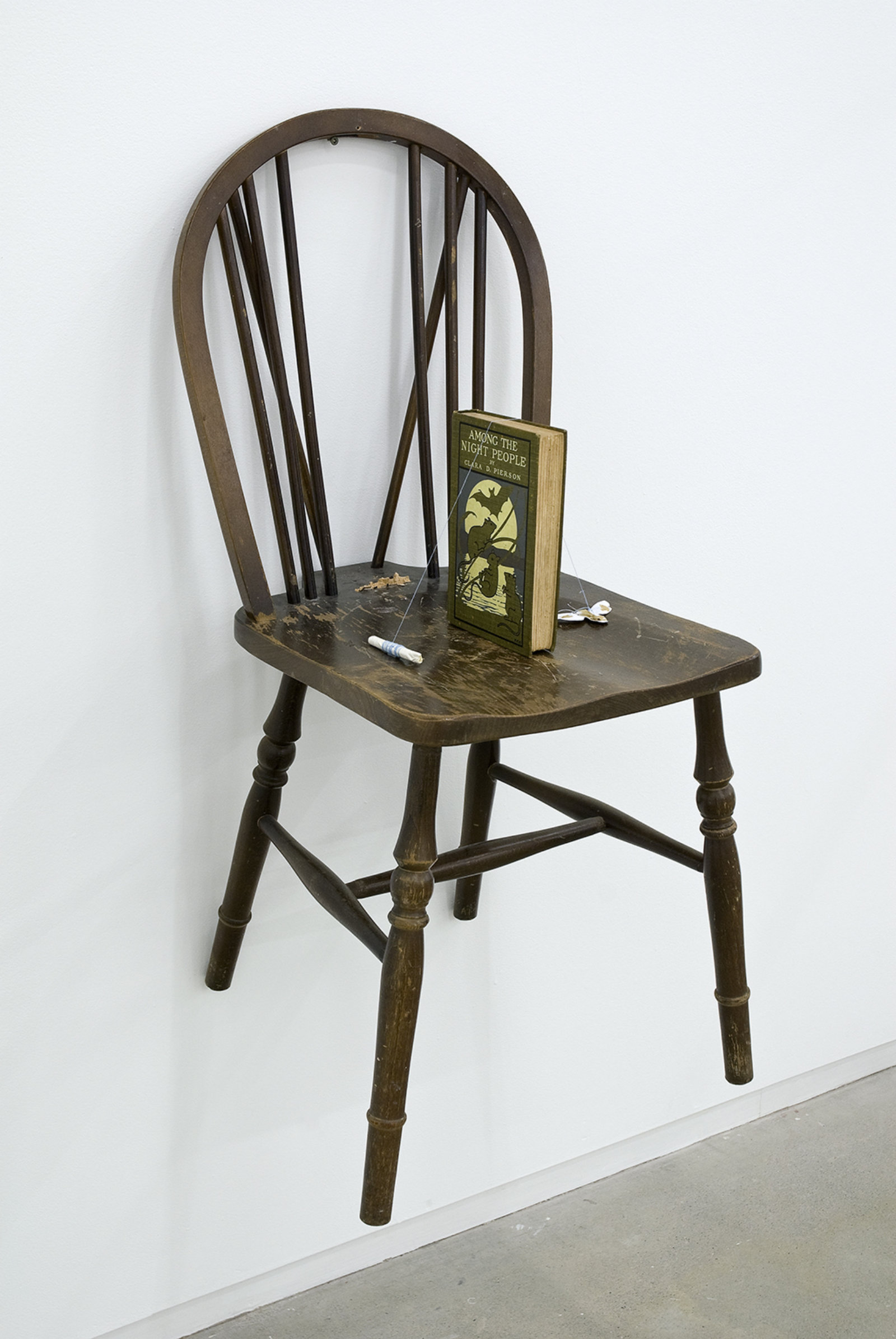 Geoffrey Farmer, I'm Not Praying I'm Just Stretching, 2008–2009, candle snuffer, abandoned Quaker-style chair taken from the streets of Boston, Among The Night People by Clara D. Pierson borrowed from the Library of the Beacon Hill Friends House, photograph of the human liberty bell (1918), branch from a tree used for public hangings in the Boston Common, light socket with the embossed words ‘proclaim liberty throughout the land’, found bell inscribed with the date 1991, a bell clapper/moth feeder made from a cotton ball soaked in a solution of sugar derived from a candy taken from a Felix Gonzales-Torres work, drinking glass, vase, antique bottle, lights, various notes, dimensions variable