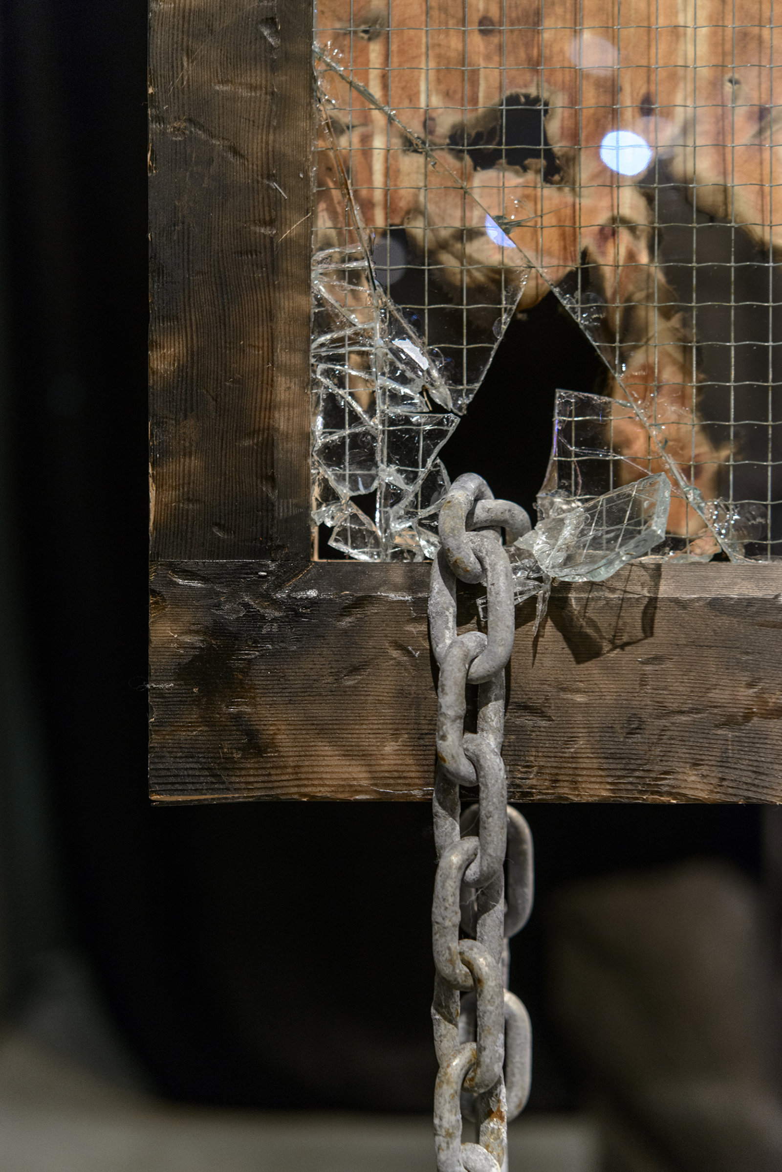 Kasper Feyrer, Chained/Charred, 2013, burnt fabric, corroded chain, security glass, hand painted sign, charcoaled wood frame, dimensions variable. Installation view, The Intellection of Lady Spider House, Art Gallery of Alberta, 2013.