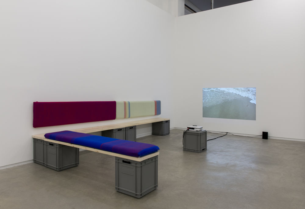 Andrea Büttner, Benches, 2013, handwoven wool backrests, spruce, plastic crates, each 37 x 78 x 16 in. (93 x 2 x 40 cm), Little sisters, Lunapark, Ostia, 2012, HDV, dimensions variable  ​ by 
