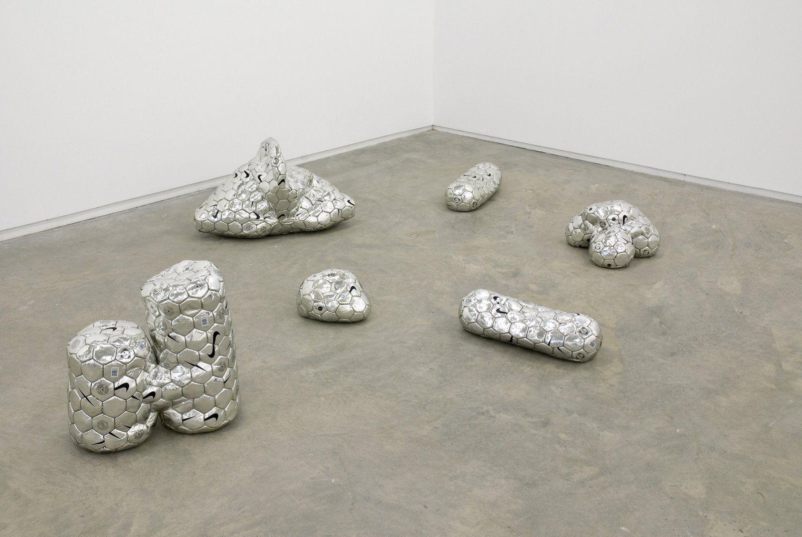 Brian Jungen, Modern Sculpture (After Iceland), 2005, 6 sculptural forms of lava rock and soccer balls, dimensions variable