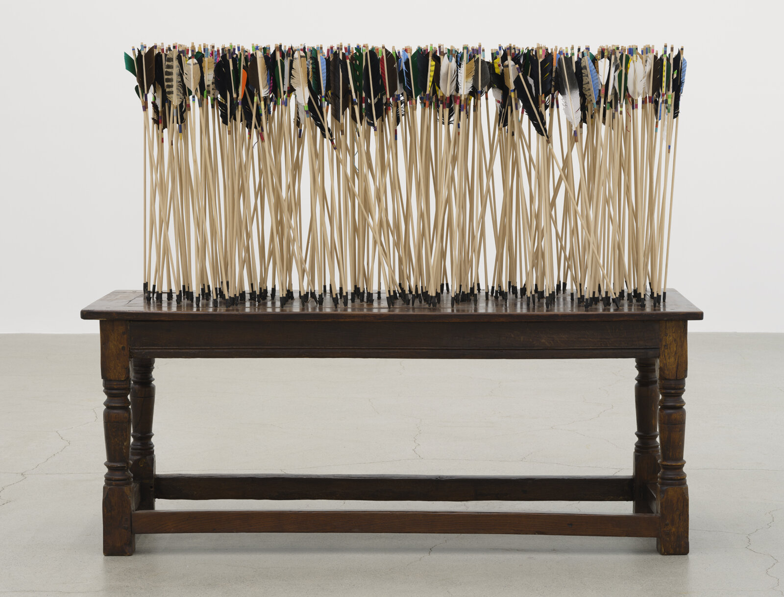 Brian Jungen, The Way of the World, 2024, 250-year-old French colonial oak table from Baton Rouge, wood arrows, carbon steel points, feather, artificial sinew, 63 x 76 x 29 in. (160 x 193 x 74 cm)