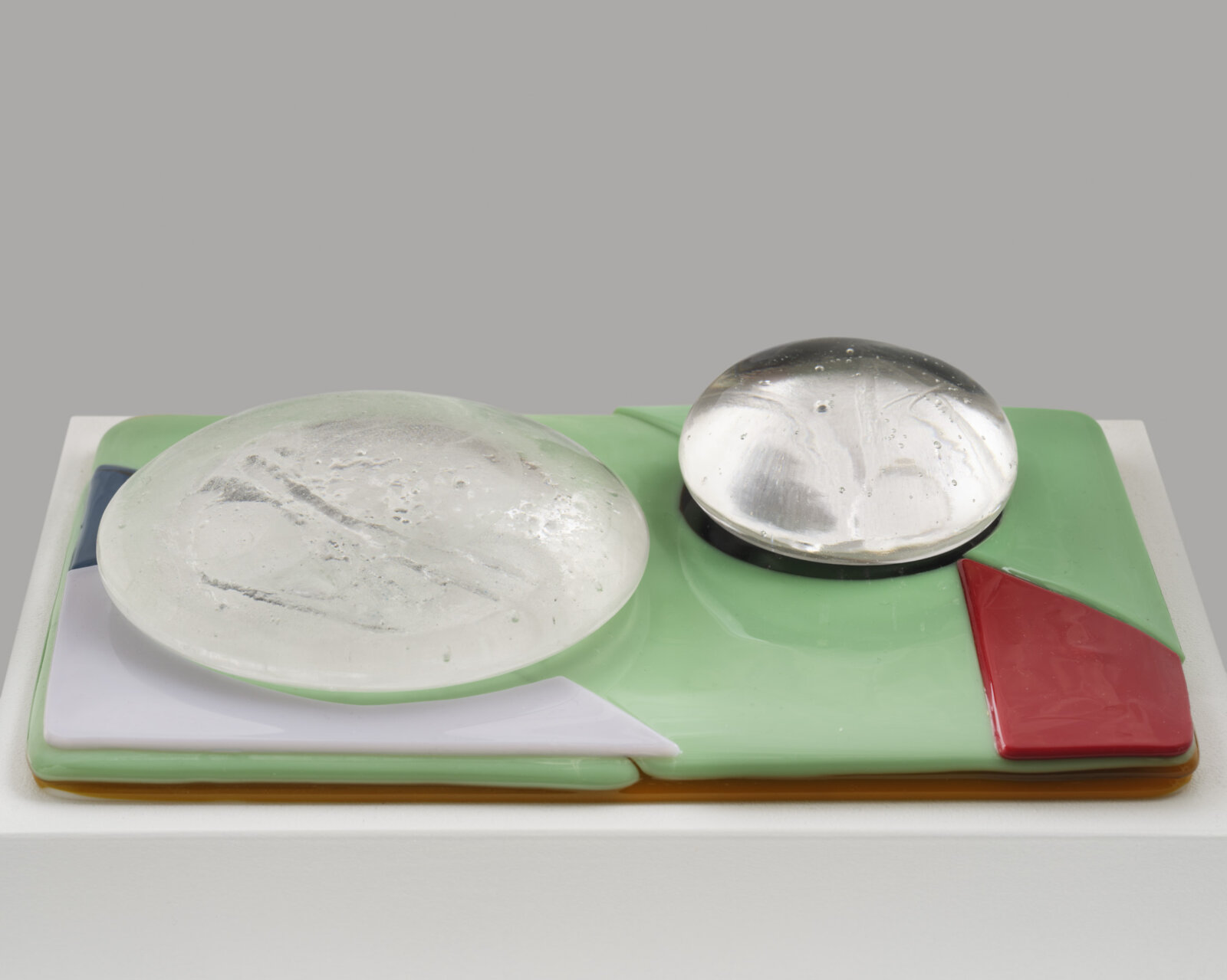 Devon Knowles, Is, Was, Here, 2022, glass, 3 parts, yellow 3 x 10 x 7 in. (6 x 25 x 18 cm); blue 3 x 10 x 7 in. (6 x 25 x 17 cm); mint 2 x 10 x 7 in. (5 x 25 x 18 cm)