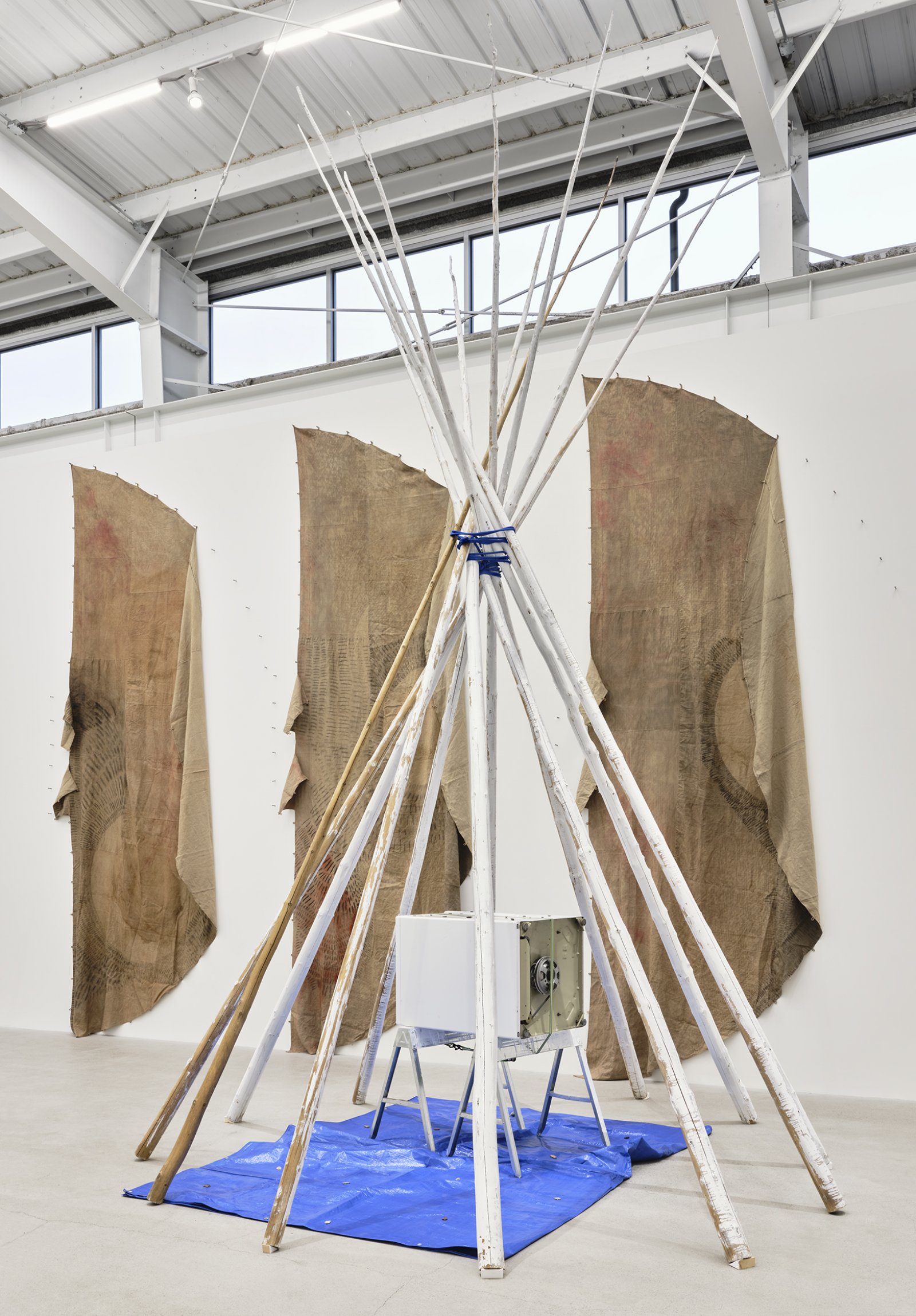 Duane Linklater, anteclovis, 2020, teepee poles, paint, nylon rope, tarpaulin, steel sawhorses, washing machine, tie-down strap, arrowheads, 230 x 158 x 158 in. (584 x 401 x 401 cm)