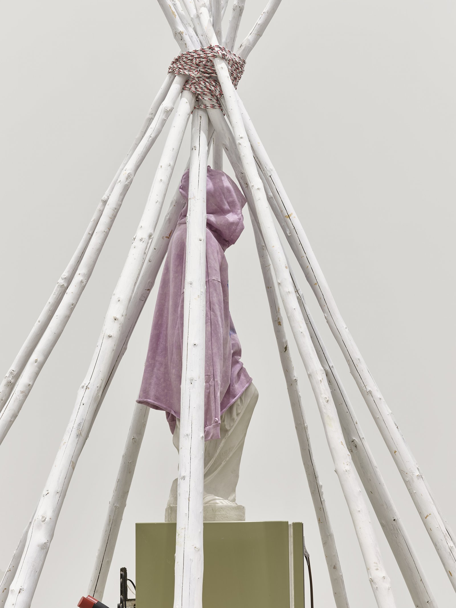 Duane Linklater, what grief conjures (detail), 2020, teepee poles, paint, nylon rope, wooden pallet, refrigerator, tie-down straps, hand truck, plastic statue, handmade hoodie, cochineal dye, silkscreen, 249 x 160 x 160 in. (632 x 406 x 406 cm)