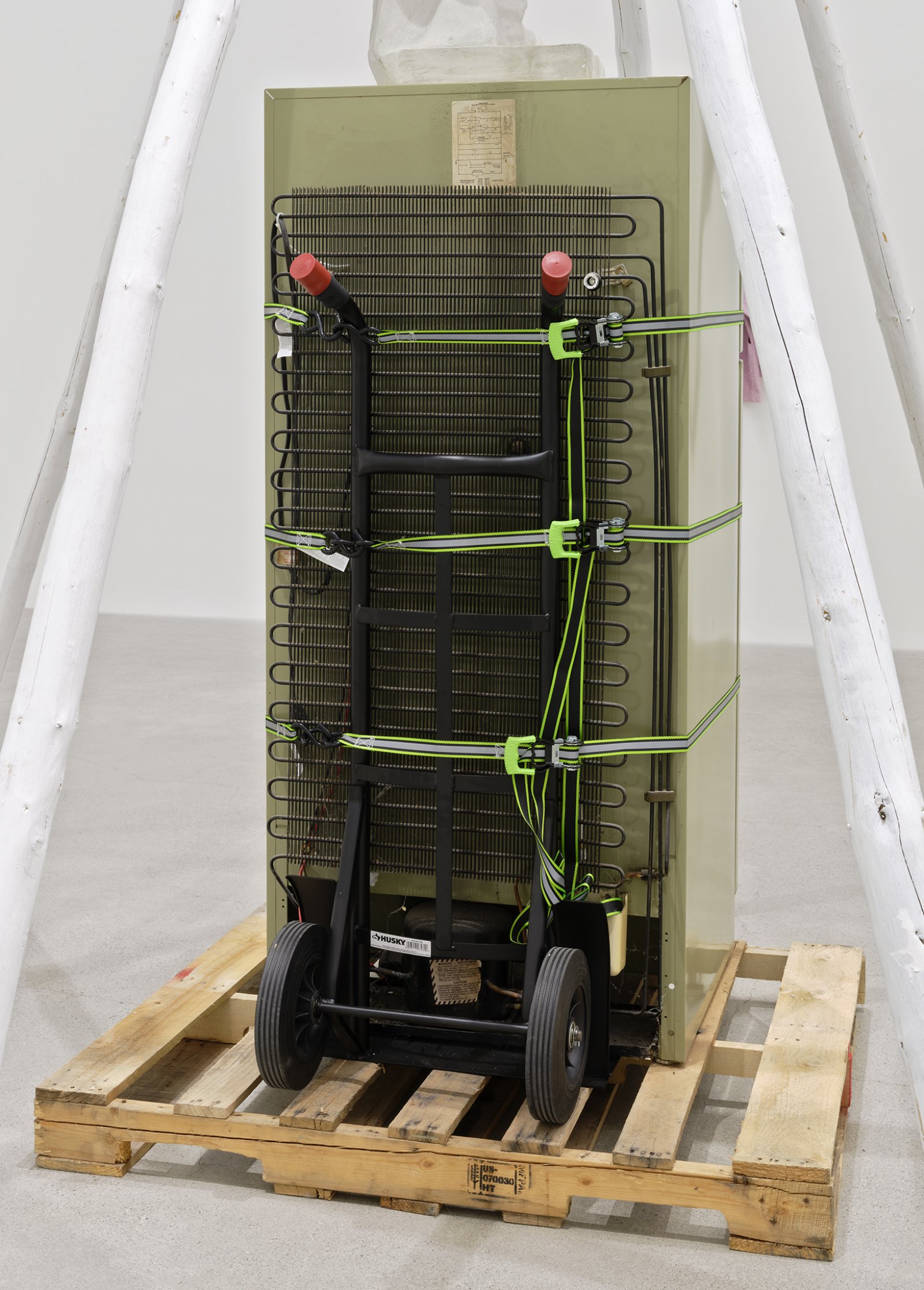 Duane Linklater, what grief conjures (detail), 2020, teepee poles, paint, nylon rope, wooden pallet, refrigerator, tie-down straps, hand truck, plastic statue, handmade hoodie, cochineal dye, silkscreen, 249 x 160 x 160 in. (632 x 406 x 406 cm)