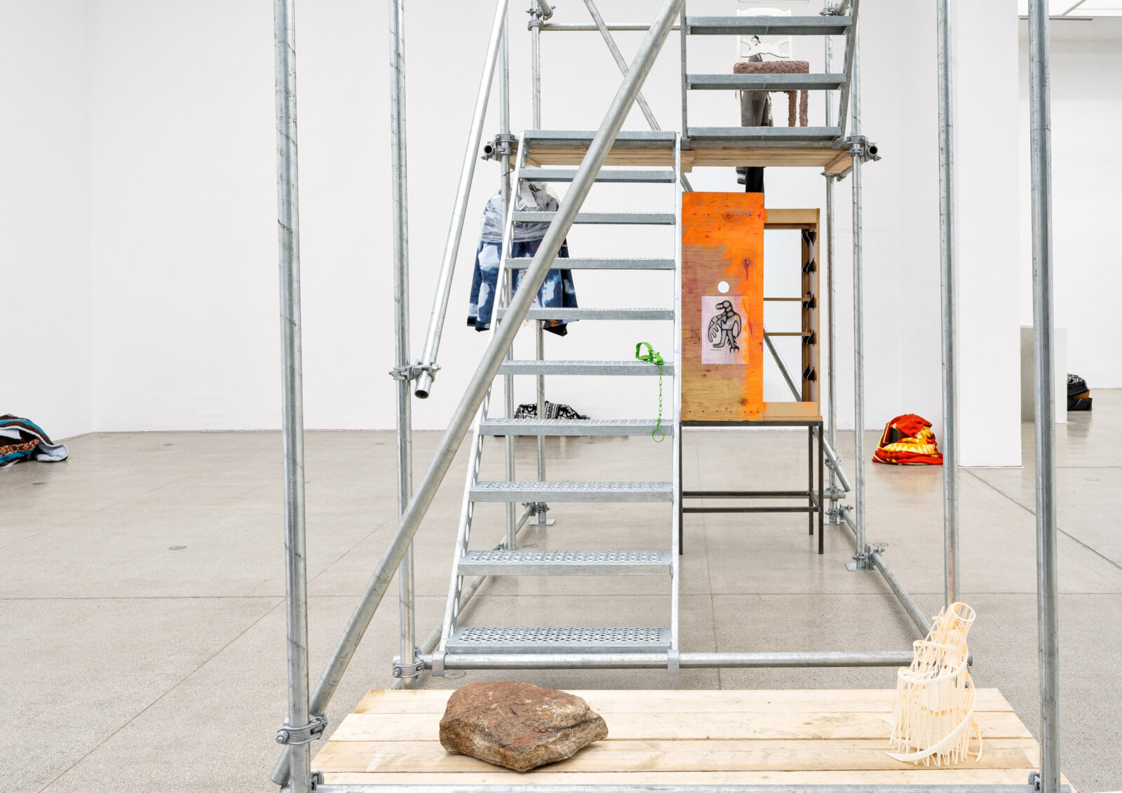 Duane Linklater, cache_littlebrother_1 (detail), 2025, steel structure, wood, fur coat with painting, stone and pigment, 3D print with spray paint, jacket with screen print, jacket with spray paint and painting, wool jacket with screen print, furniture with spray paint and digital print, chair with soil, clay, grass, water, powder coated steel trap, 158 x 197 x 79 in. (400 x 500 x 200 cm)