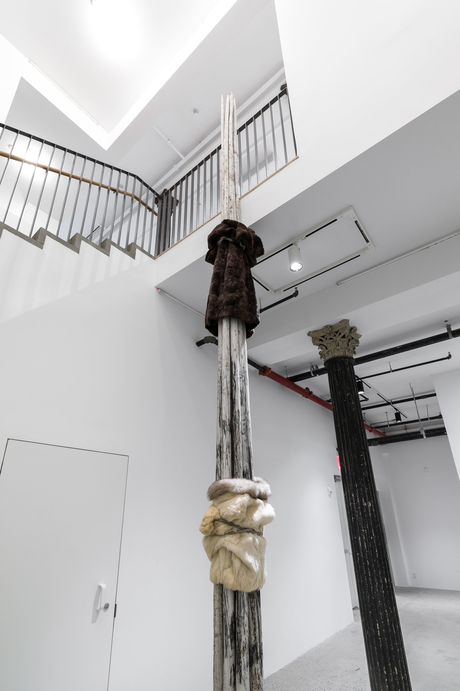 Duane Linklater, landlesscolumnbundle (detail), 2019, tipi poles, white paint, charcoal, rabbit fur coat, mink fur coat, rope, 243 x 10 x 10 in. (617 x 25 x 25 cm). Installation view, Artists Space, New York, USA, 2019