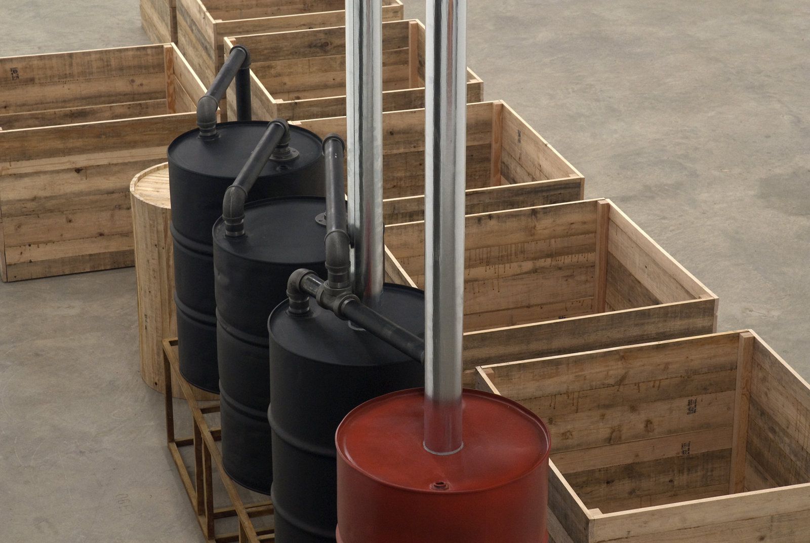 ​Myfanwy MacLeod, Everything Seems Empty Without You, 2009, metal oil drums, metal sand, metal pipes, wooden boxes, wooden barrel, 118 x 332 x 94 in. (300 x 843 x 239 cm) by 