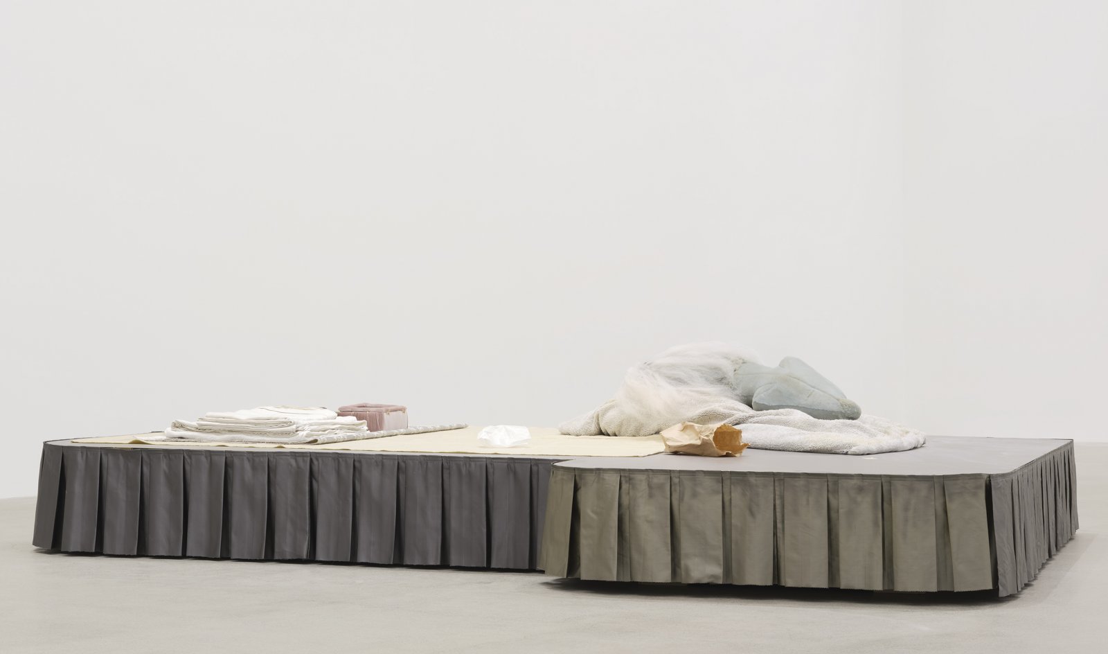 ​Liz Magor, Coiffed, 2020, painted plywood, fabric skirting, silicone rubber, artificial hair, acrylic throw, woollen blankets, silver fabric, linen, jewellery boxes, costume jewellery, packaging materials, 27 x 132 x 96 in. (69 x 335 x 244 cm) by Liz Magor