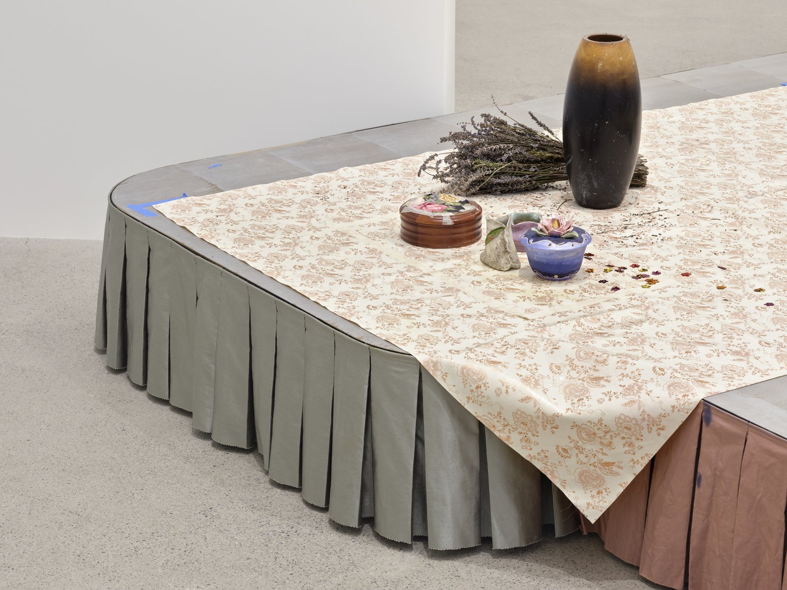​​Liz Magor, Dressed (detail), 2020, painted plywood, fabric skirting, silicone rubber, hosiery, sheepskin, vinyl tablecloth, wood and ceramic crafts, plastic cup, dried lavender, packaging materials, 28 x 120 x 108 in. (71 x 305 x 274 cm)​ by Liz Magor