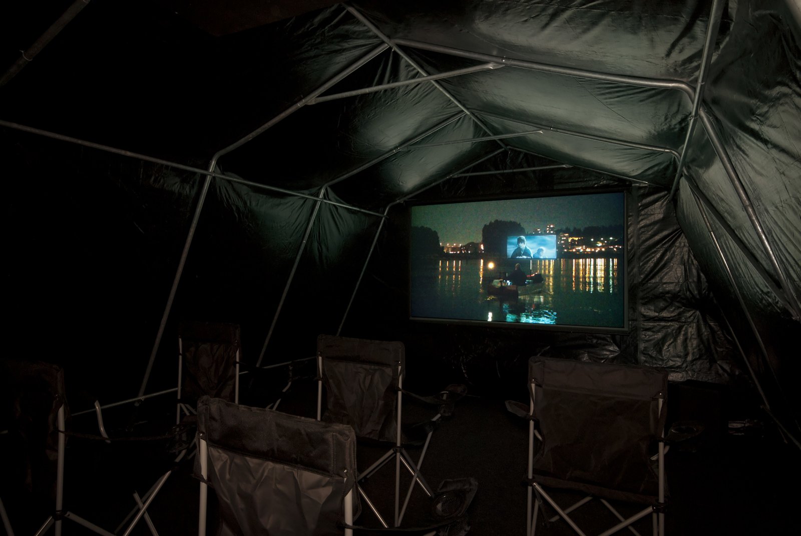 Kevin Schmidt, Autonomous Projection Room #1, 2010, tarp, portable garage frame, carpet, roxul, projector, home stereo system, screen, batteries, inverter, camping chairs, 181 x 60 x 105 in. (460 x 152 x 267 cm)
