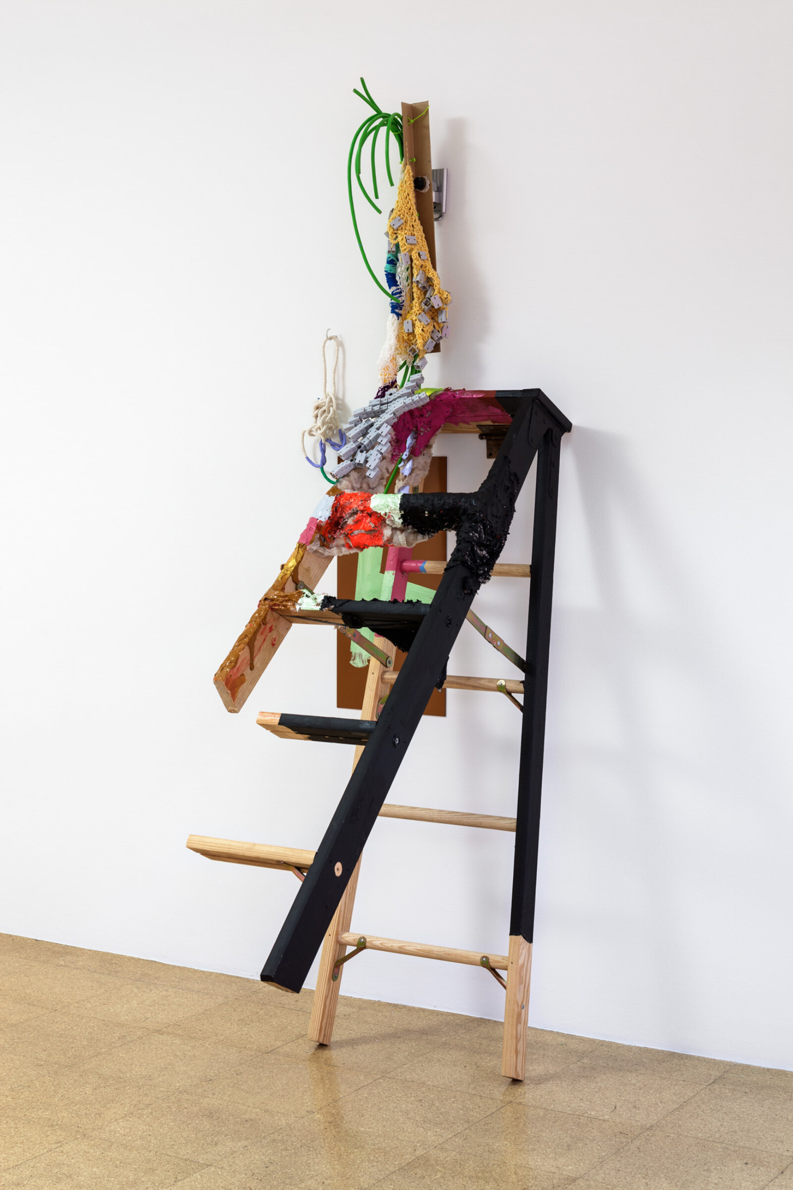 Jessica Stockholder, A - H, 2013, ladder, brass, plastic toy modules, yarn, string, extension cord, plexiglas, rope, acrylic paint, fake fur, cardboard, zip ties, TV mount, white hook, hardware, 85 x 27 x 49 in. (215 x 69 x 125 cm)