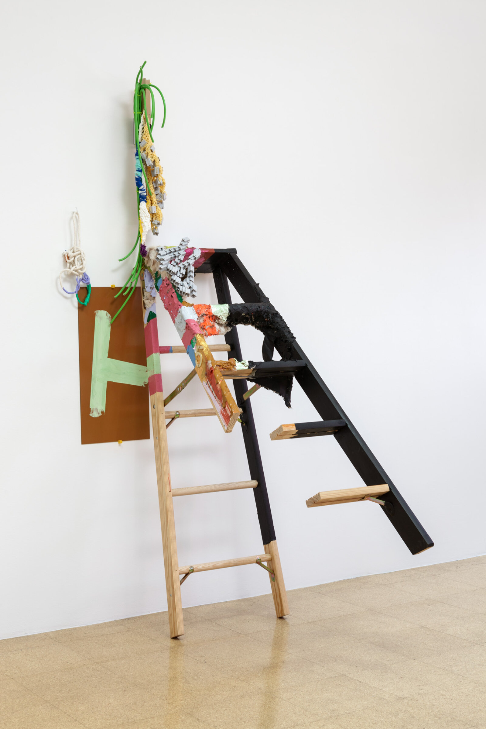Jessica Stockholder, A - H, 2013, ladder, brass, plastic toy modules, yarn, string, extension cord, plexiglas, rope, acrylic paint, fake fur, cardboard, zip ties, TV mount, white hook, hardware, 85 x 27 x 49 in. (215 x 69 x 125 cm)