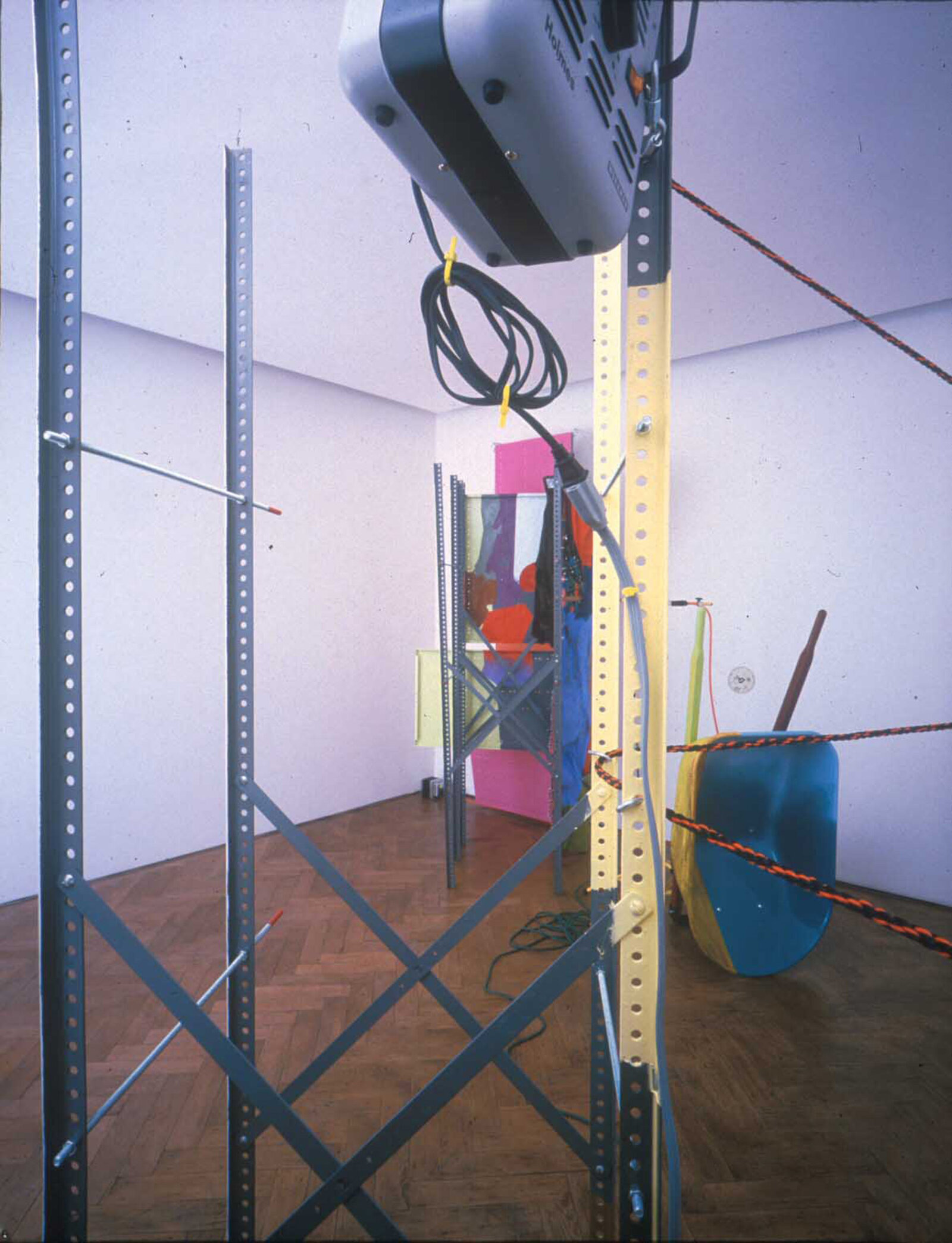 Jessica Stockholder, Coupling, 1998, metal shelving elements, threaded rod, carpet, fur, blankets, clothing, oil-based enamel paint, oil paint, acrylic paint, wheel barrow, light stand, extension cords, rope, hardware, brass and wooden threshold plates, space heater with fan, 166 x 149 x 111 in. (422 x 378 x 281 cm)