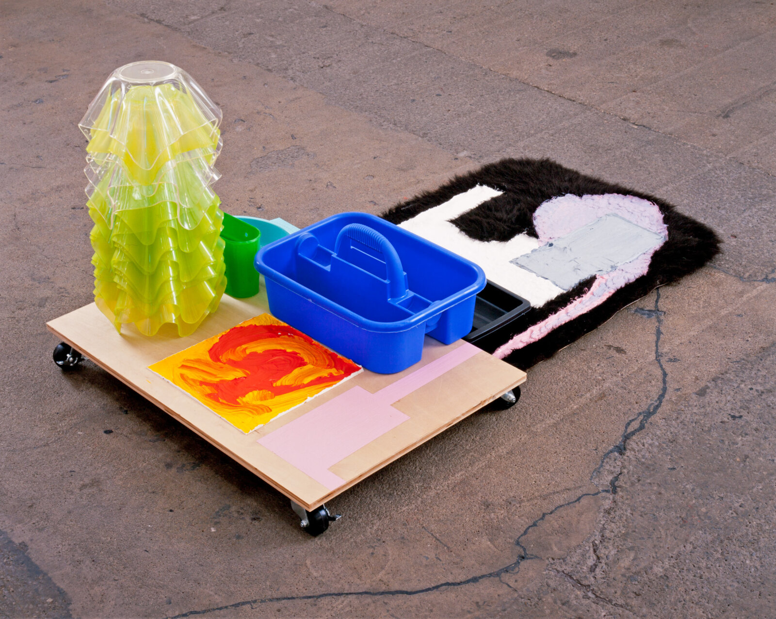 Jessica Stockholder, JS389, 2003, plywood with wheels, stack of 17 green and clear plastic bowls, 4 other plastic parts, rug, acrylic paint, 61 x 35 x 27 in. (155 x 89 x 69 cm)