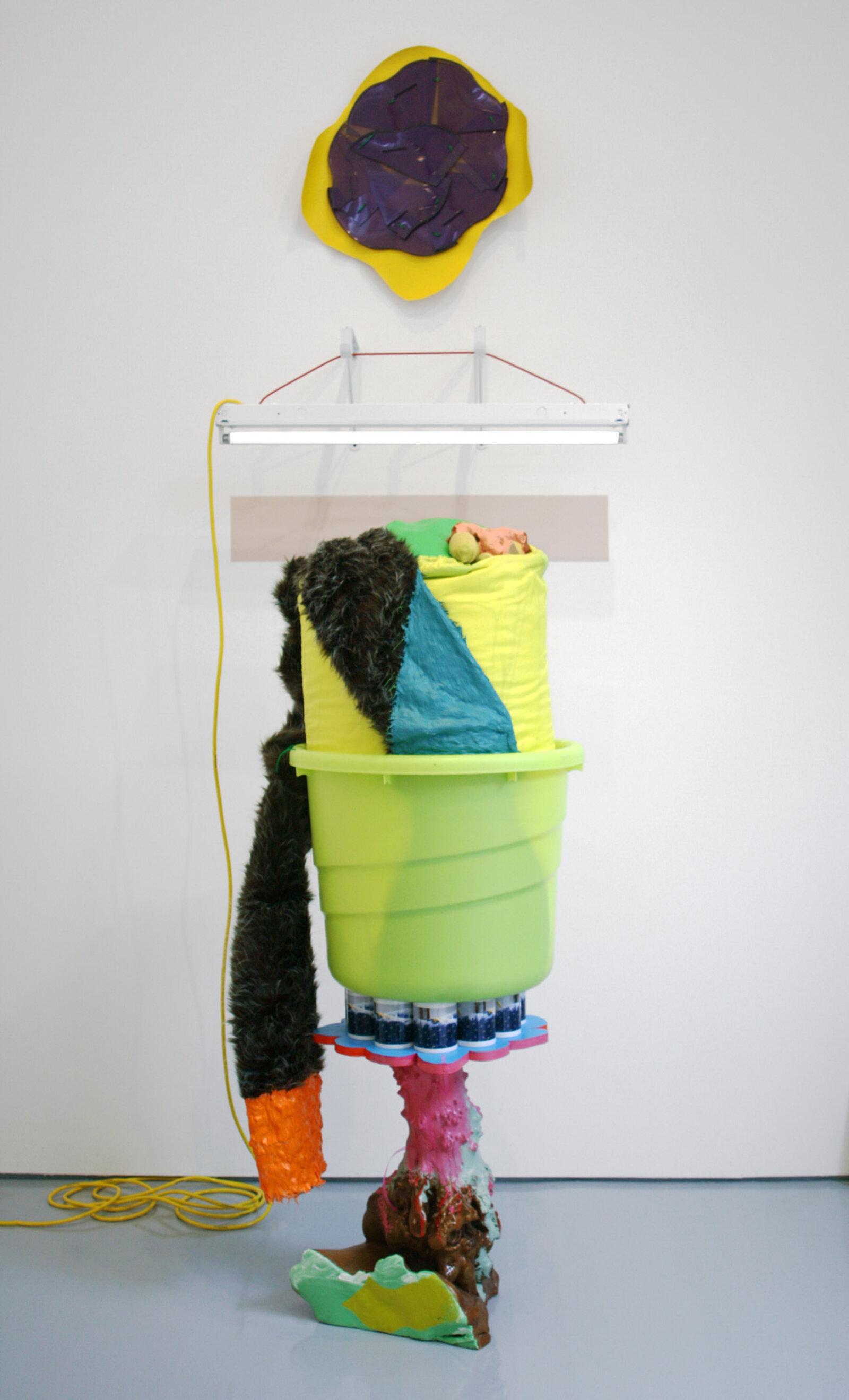 Jessica Stockholder, JS491, 2009, vinyl, fluorescent fixture, electric cord, cable, hardware, plastic tub, laundry bag, styrofoam stuffing, artificial lemons, acrylic and oil paint, coffee mugs with custom image, wooden base, ribbon, fake fur, plastic parts, 109 x 37 x 40 in. (277 x 94 x 102 cm)