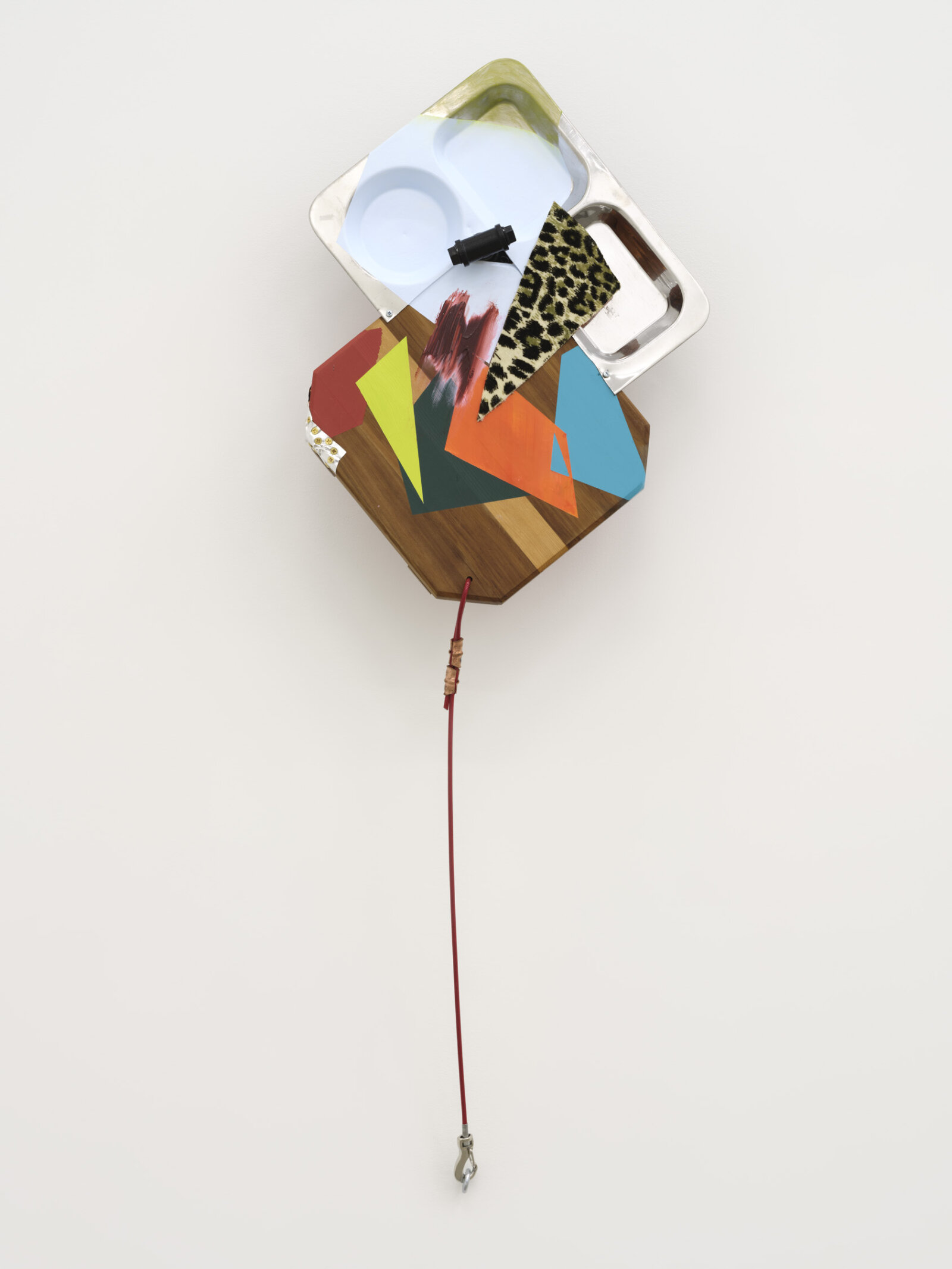 Jessica Stockholder, That soft patch behind the knee poked by the snow covered peak, 2025, wooden chopping board, metal tray, acrylic paint, oil paint, fabric, caulking, foil, cable, hardware, 47 x 16 x 7 in. (118 x 41 x 18 cm)